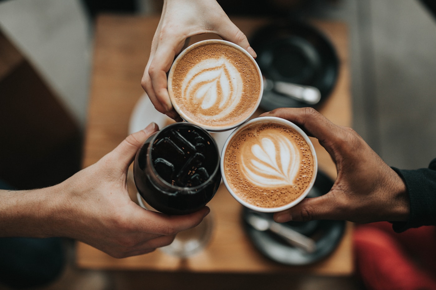 An overhead pour of a latte with a tulip pattern, on a warm wooden café counter.